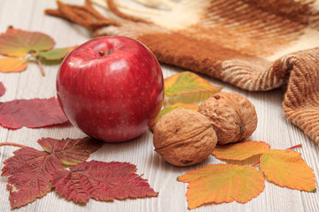 Apple, walnuts and dry leaves in an autumn still llife.