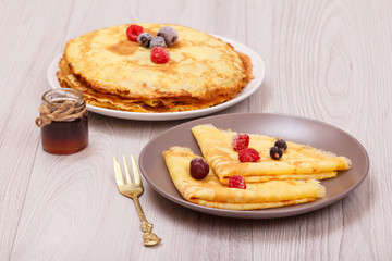 Homemade pancakes on plates and fork on wooden desk.