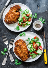 Tempura chicken chop with rice and fresh vegetable salad on a dark background, top view