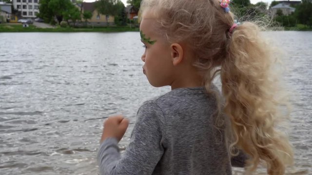 Pretty blond girl simper in front of camera on lake background. Gimbal motion