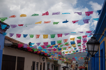 Colorful Papel Picado Hanging on Streets in Chiapas, Mexico with Stormy Sky Behind