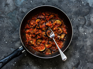 Tomatoes eggplant pasta sauce in a pan on a dark background, top view