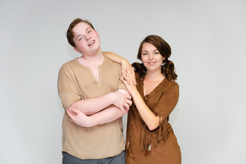 Portrait below the belt on a white background pretty young brunette woman in a brown dress and a young man in a brown shirt. Standing in different poses, talking, showing emotions.