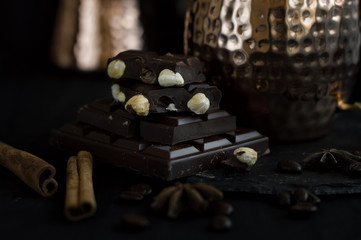 Dark chocolate with hazelnut served on a slate board with metal mug, cinnamon sticks and anise. Dessert for morning coffee