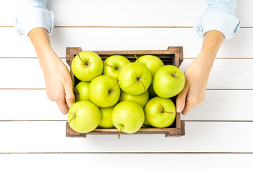 Hands holding wooden crate with apples. Top view