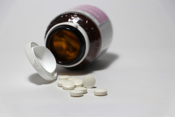 Pile of round white medicine on the floor, it came out of the falling medicine bottle. Medical concept.