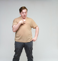 Portrait of a knee on a white background cute young man in a brown T-shirt in jeans. Standing right in front of the camera in various poses, talking, demonstrating emotions.