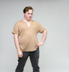 Portrait of a knee on a white background cute young man in a brown T-shirt in jeans. Standing right in front of the camera in various poses, talking, demonstrating emotions.