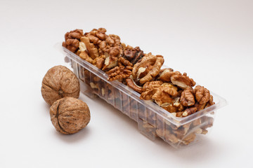 Walnuts in a plastic container on the white background.