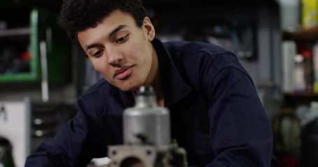 4K Happy young mechanic with job satisfaction fixing vehicle engine in the shop