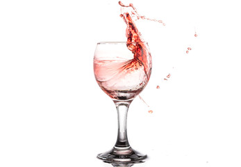 Red wine splash in a round glass on a white background