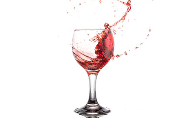 Red wine splash in a round glass on a white background