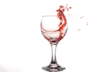 Red wine splash in a round glass on a white background