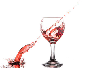 Red wine splash in a round glass on a white background