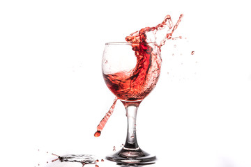 Red wine splash in a round glass on a white background