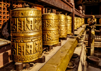 A prayer wheels on a spindle made from metal and wood. Mantra Om Mani Padme Hum is written in...