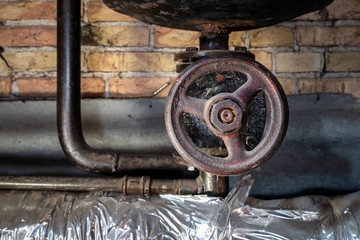 Fototapeta na wymiar Rusty valves on boiler room pipes. Old metal boiler generating heating and delivering it to home through pipeline