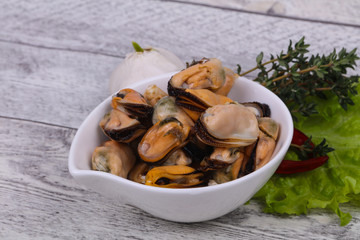 Pickled mussels in the bowl served pepper, garlic and salad