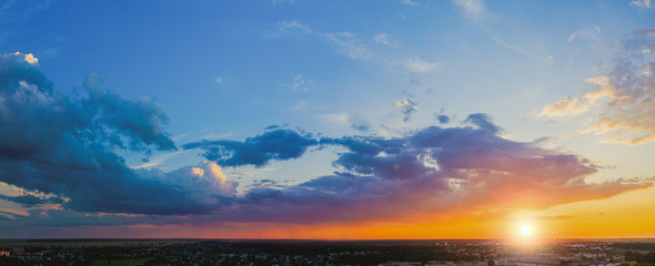 Panorama of the evening sky at sunset with beautiful cumulus clouds above the city