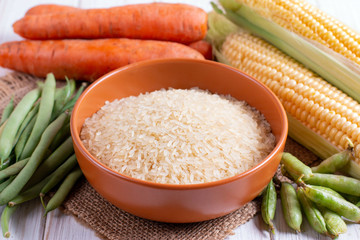 Rice in a ceramic bowl on the background of vegetables