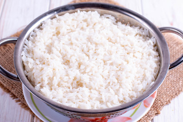 Cooked rice in a colander on a wooden table