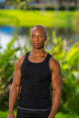 Portrait of a muscular fitness model posing in the park. Image lit with off camera flash