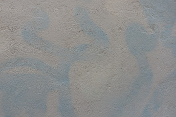 Two color wall with new white paint painted over blue graffiti letters