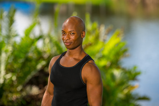 Portrait of a handsome fitness model posing in a park setting. Image taken with off camera lights and blurry background