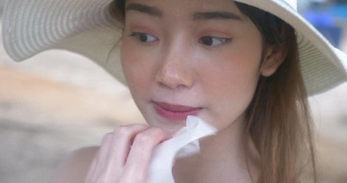 Woman cleaning oil on her skin face with a facial tissue paper.