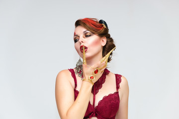 Naklejka premium Portrait to the waist on a white background of a pretty young brunette woman with beautiful makeup, with gold jewelry on her hand. Beauty, great makeup. Shows emotions.