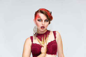 Portrait to the waist on a white background of a pretty young brunette woman with beautiful makeup, with gold jewelry on her hand. Beauty, great makeup. Shows emotions.