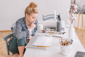 woman with a finger on her lips is going to draw a sketch in the art studio. creativity, talent...