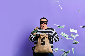 plump thief is surprised at much money in the sack. happiness concept. isolated blue background