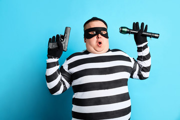 nervous unhappy burglar is being cought by police, isolated blue background. studio shot