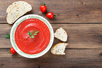 Tomato soup in bowl on wooden background. Top view.