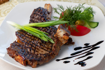 grilled beef steak with sauce and vegetables on a white plate