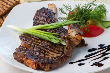 grilled beef steak with sauce and vegetables on a white plate