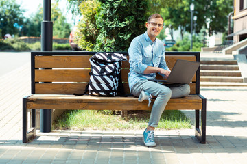 Fototapeta premium Smiling freelancer feeling busy while finishing work sitting on the bench
