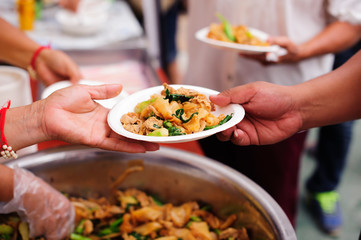 Concept of food sharing for the poor to alleviate hunger : Hands of beggars accepting food from the hands of volunteers who come to help free food breaks