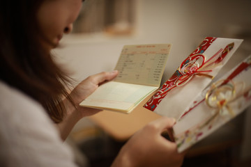 通帳を見ながらご祝儀を悩む女性