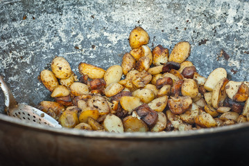 Roast potatoes in a large pan. Delicious food at the festival. Field kitchen at the hearth.