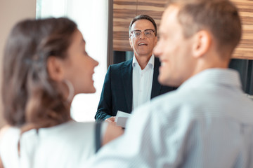 Mature realtor looking at couple while talking to them