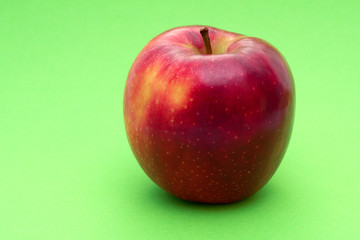 Big red apple on green background.