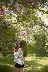 Fototapeta na wymiar Girl smelling lilac green park.