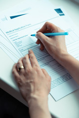 Woman holding pen and signing papers buying medical insurance