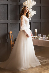 Naklejka premium Portrait of the beautiful bride. Bride with makeup and hairstyle in a luxury long wedding dress. Elegant hair accessorie. Studio indoor photo.