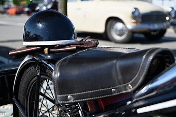 Old black helmet resting on gloves on a veteran motorcycle.