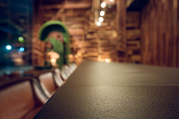 Empty wooden bar counter with defocused background and bottles of restaurant, bar or cafeteria background.