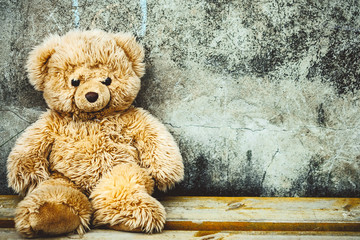 Teddy bear toy on the bench at the concrete wall with small tic tac toe game