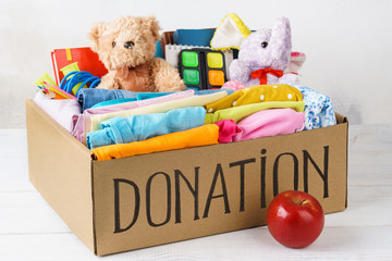 Different donations in a box - clothes, stationery and toys.